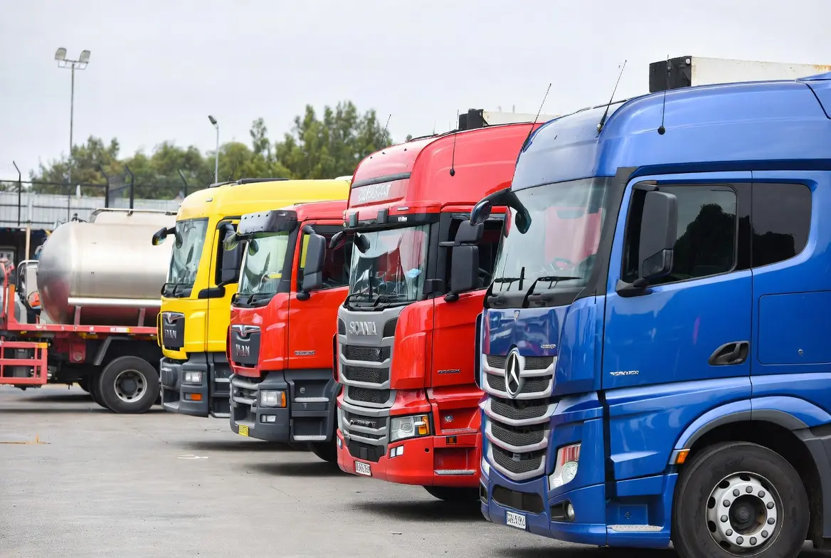 Close up of yellow MAN, red Scania and blue Mercedes heavy-duty trucks parked together at a commercial truck auctioneers yard in South Africa showing quality vehicles available at auction